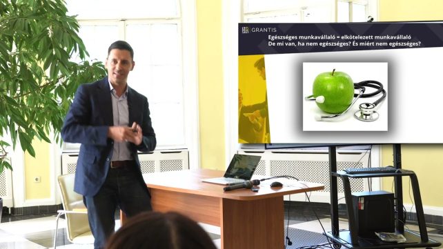 Öltönyös férfi pénzügyi előadást tart egy teremben
